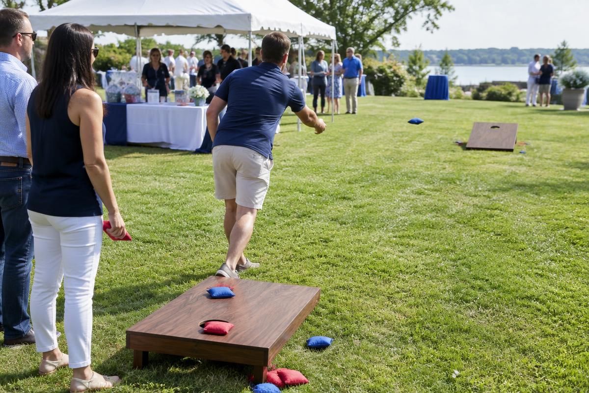 Families playing cornhole near a community fundraiser pavilion